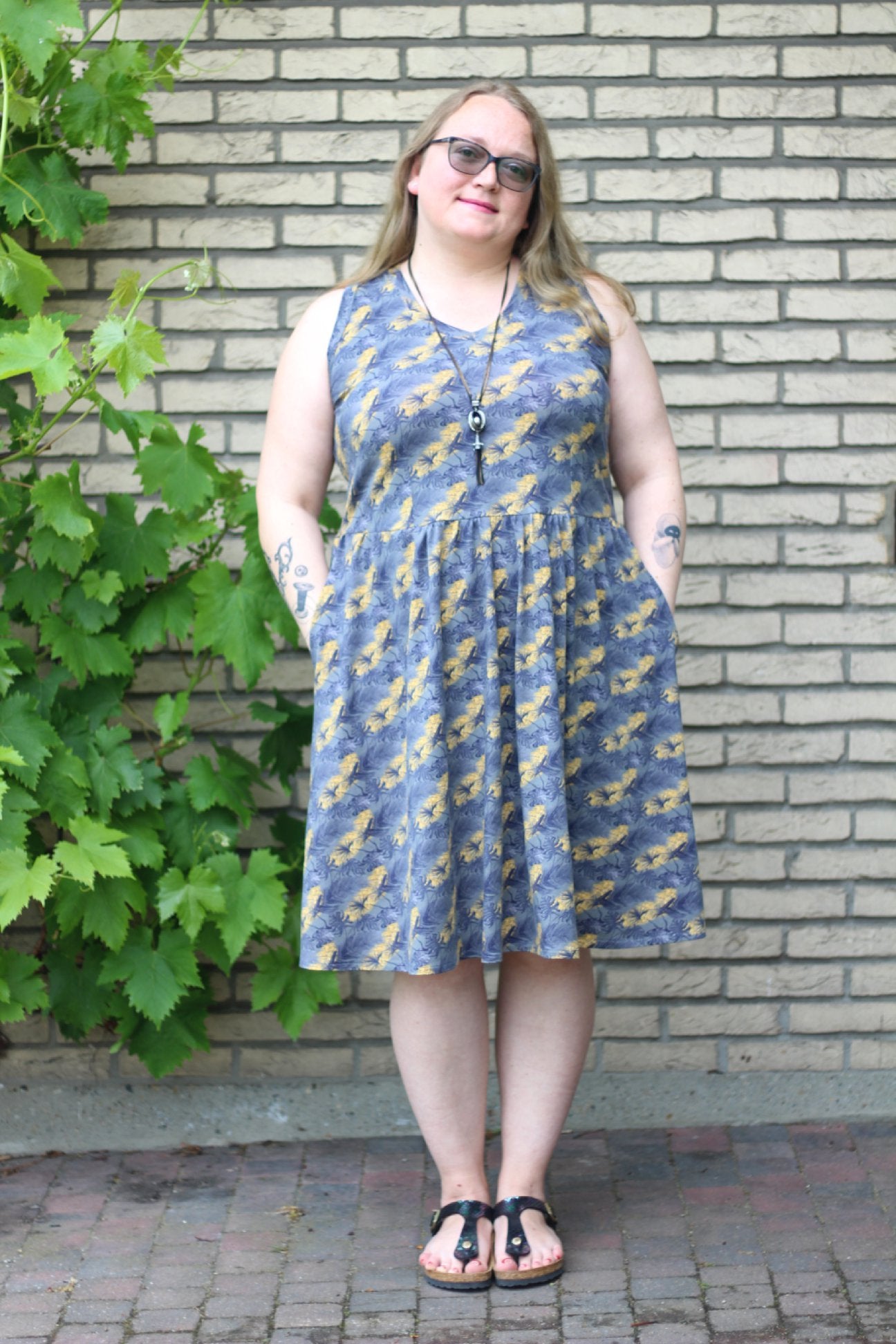 Plus size sleeveless Emmeline featuring a v-neck, pockets, and knee-length skirt. 