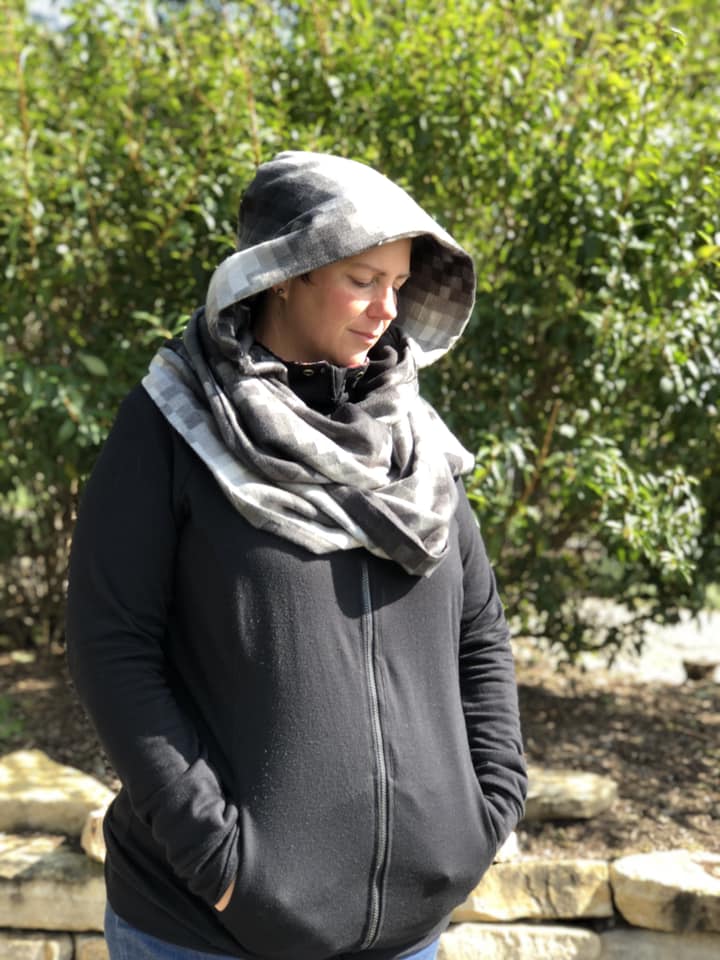 Pattern tester displaying the Hooded Infinity Scarf. Hood is up. Main fabric and lining are a gray gingham. 