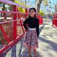 Girl standing on a bridge with a black sweater and a pink enchanted overlay skirt