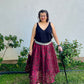 Woman standing with a cane next to a small garden wearing the enchanted overlay skirt with a dark red lace overlay and a black tank top.