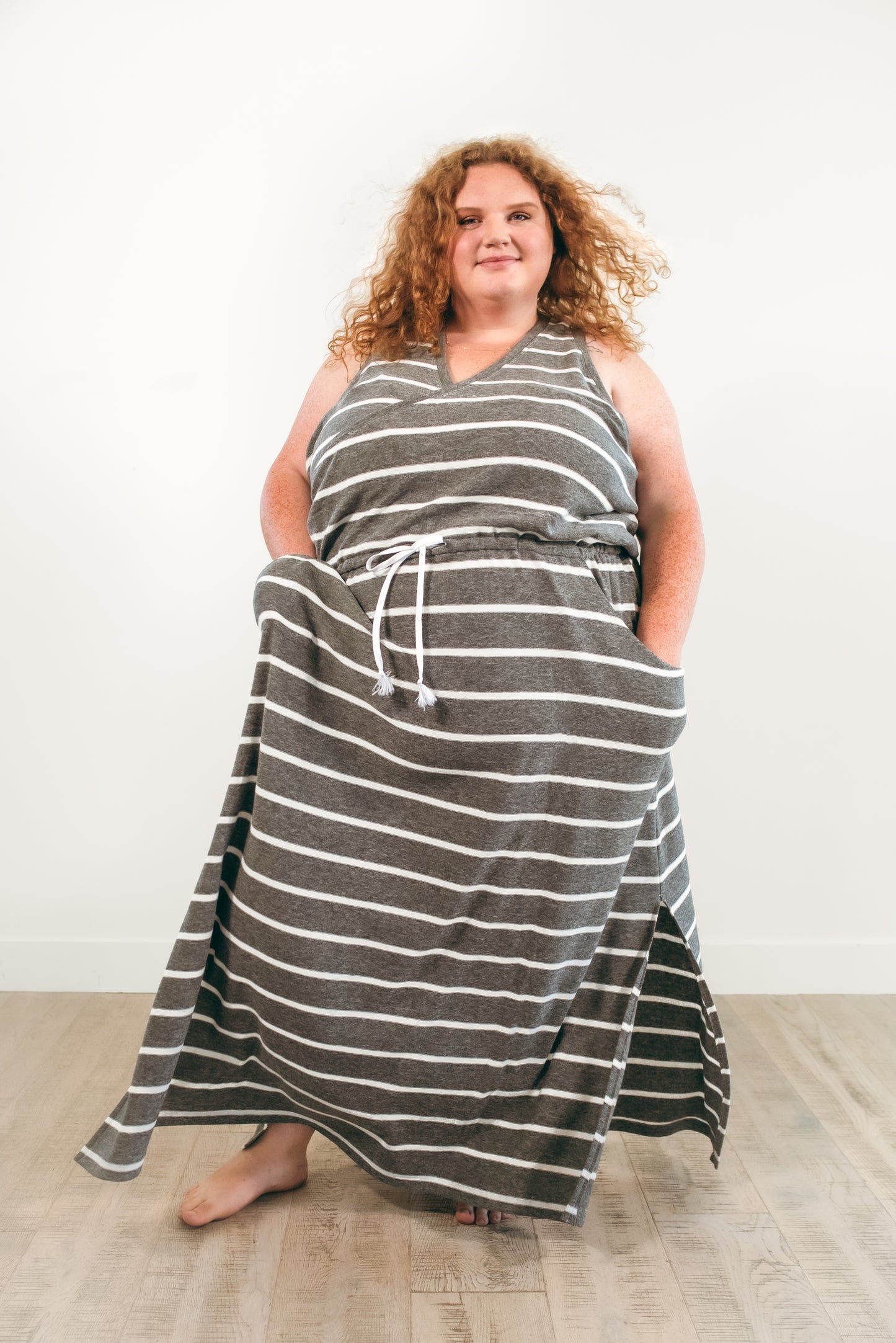The Helen dress in plus size. Features a crossover racerback bodice, maxi-length skirt with a split hem, and pockets. 