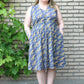 Plus size sleeveless Emmeline featuring a v-neck, pockets, and knee-length skirt. 