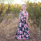 A young girl is wearing the Samantha Dress with short sleeves and a maxi length. Features a floral pattern. 