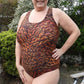 Woman wearing DIBY Club Amelia one-piece swimsuit with brown, orange and black pattern.