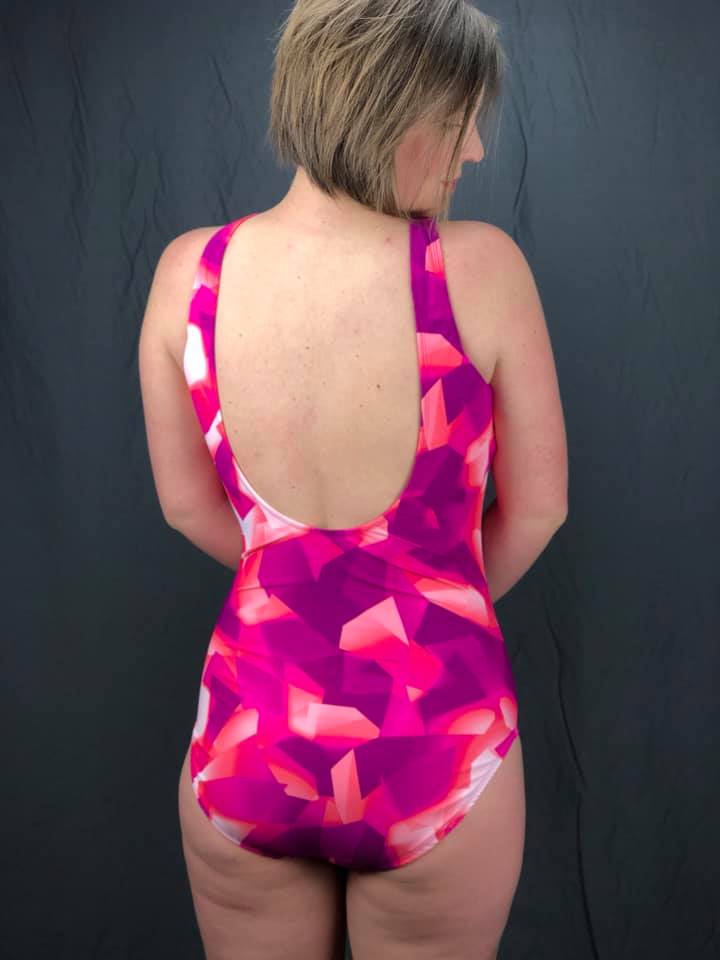 Backview of Amelia one-piece swimsuit made from a pink, purple, and white geometric fabric.
