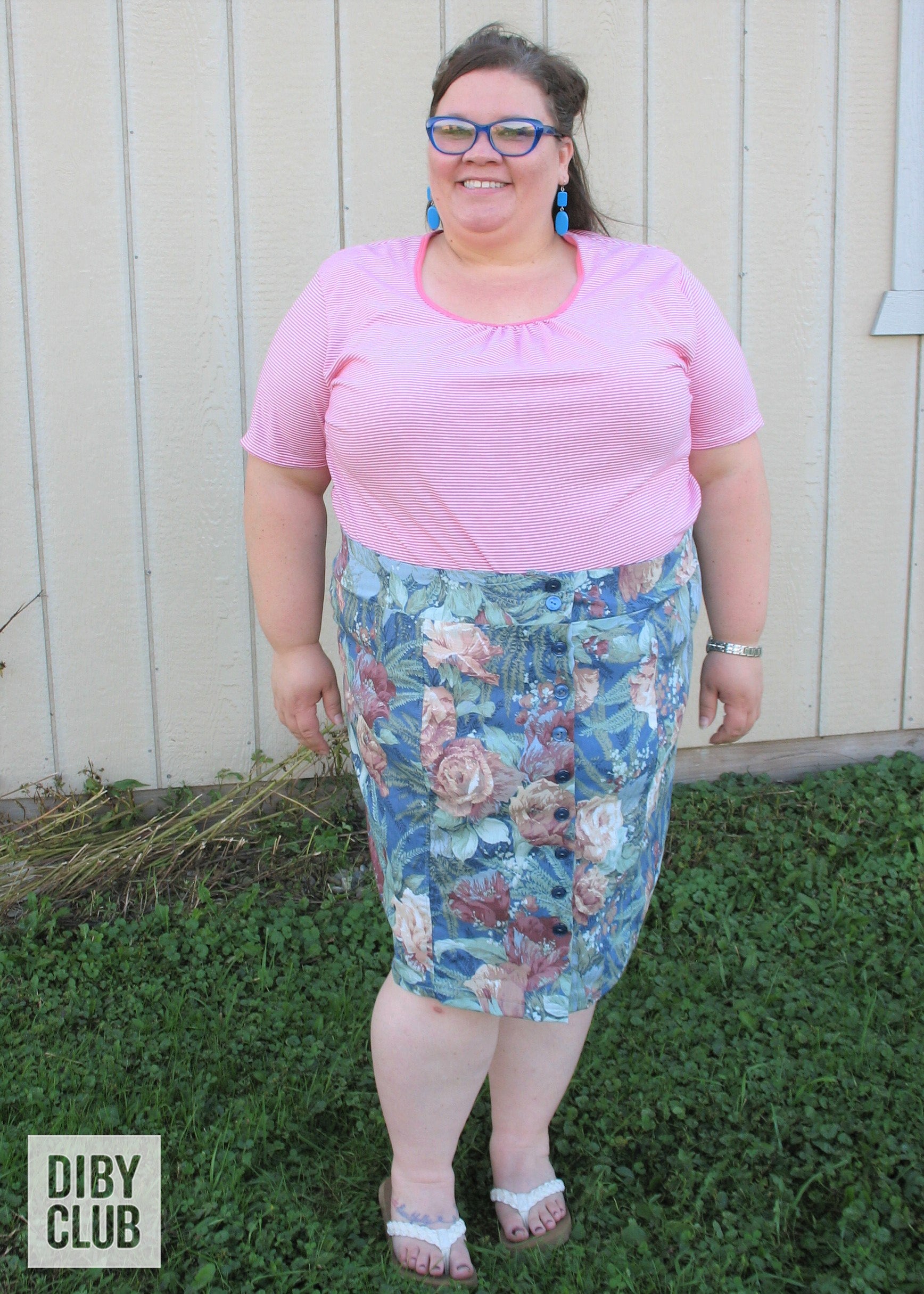 Full-length view of plus size woman wearing blue and green knee length DIBY Club Anna Button-Up skirt with dark blue buttons. Her shirt is tucked in showing the waistband.