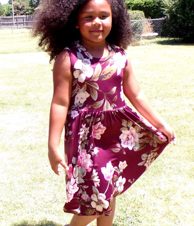 A young girl wearing a sleeveless, mid length version of the Samantha Gathered Dress. 